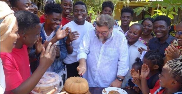 Pater Frido Pflüger SJ inmitten junger Menschen bei einer Feier